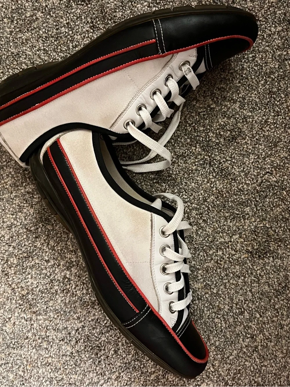 Donald J Pliner white canvas and black leather sneakers with red trim.